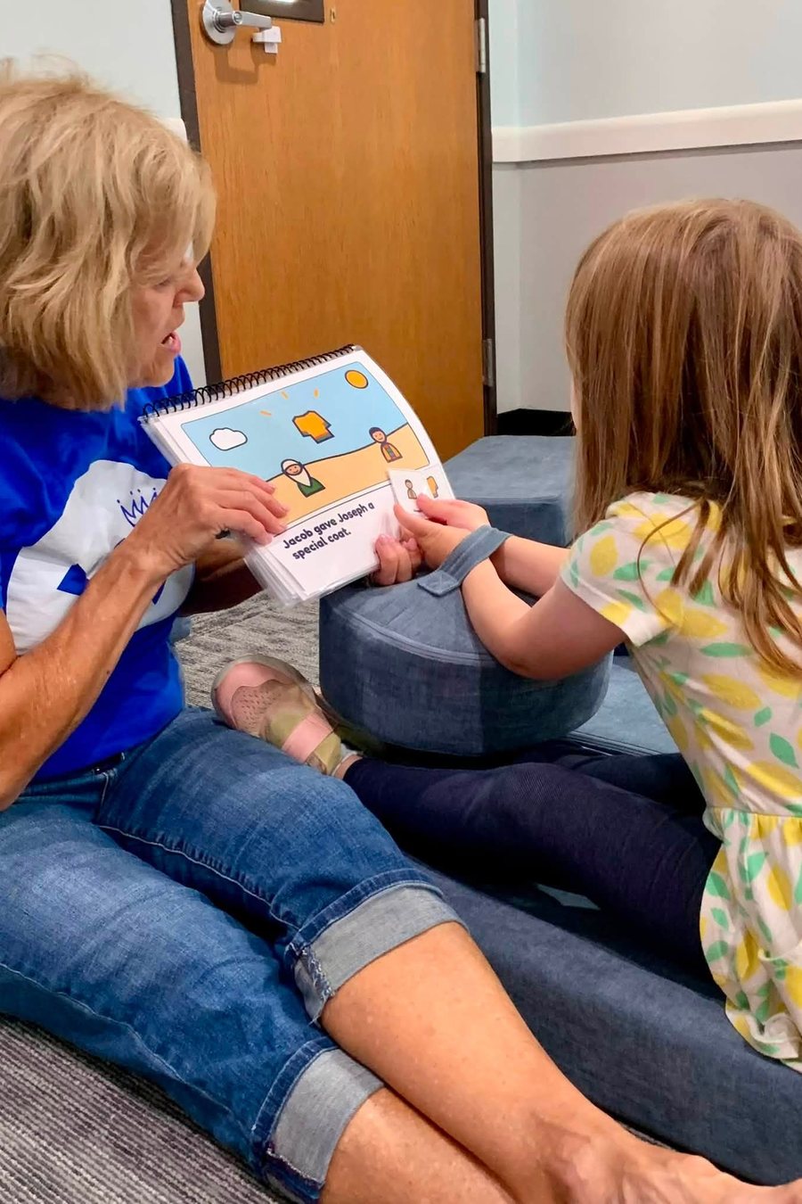 A Kingdom Kids leader reading a picture book with a young girl
